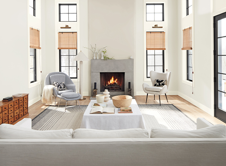 A spacious off-white painted living room with black window mullions and neutral decor.