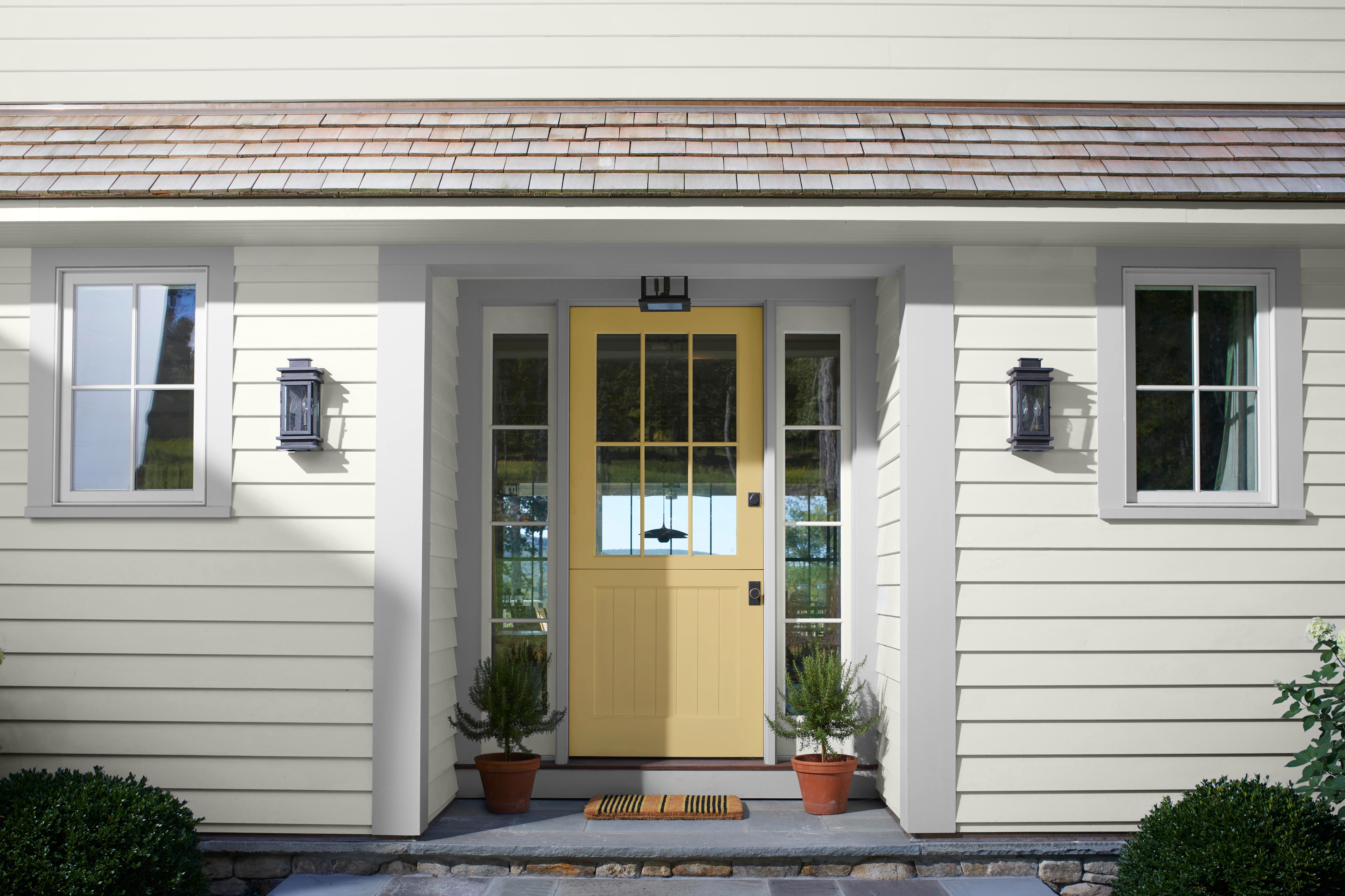 A white-painted home exterior with a yellow-gold front door, and light gray trim. 
